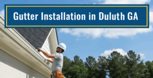 A construction worker in a white hard hat and work pants stands on a ladder, diligently installing a new white gutter on the side of a light-colored residential home. Sections of gutter and tools are laid out on a black tarp on the lawn. Other houses and dense green trees are visible in the background under a clear blue sky. The image features a top banner in badge blue with the title "Gutter Installation in Duluth GA" in white text, bordered by canary yellow.